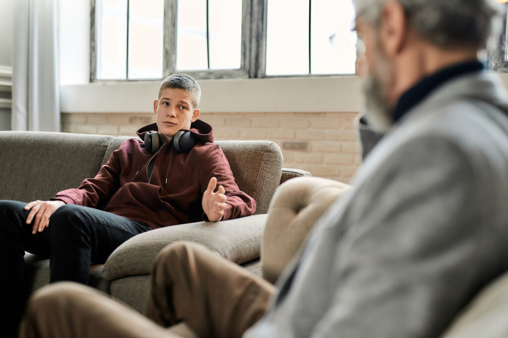 Upset teenage boy talking to professional psychotherapist